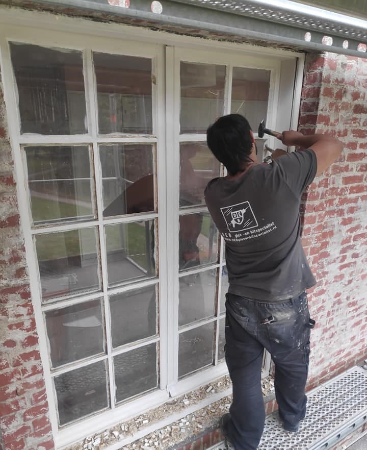 Old sealant being removed from window frame by DEB employee