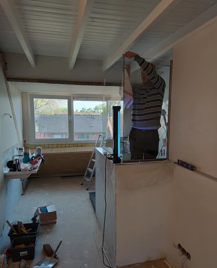 Glass shower wall being installed in place